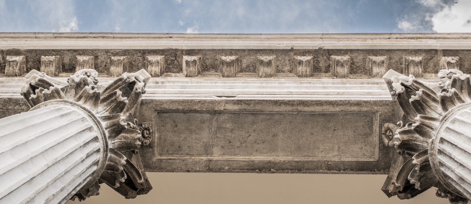 Looking up at old columns against sky