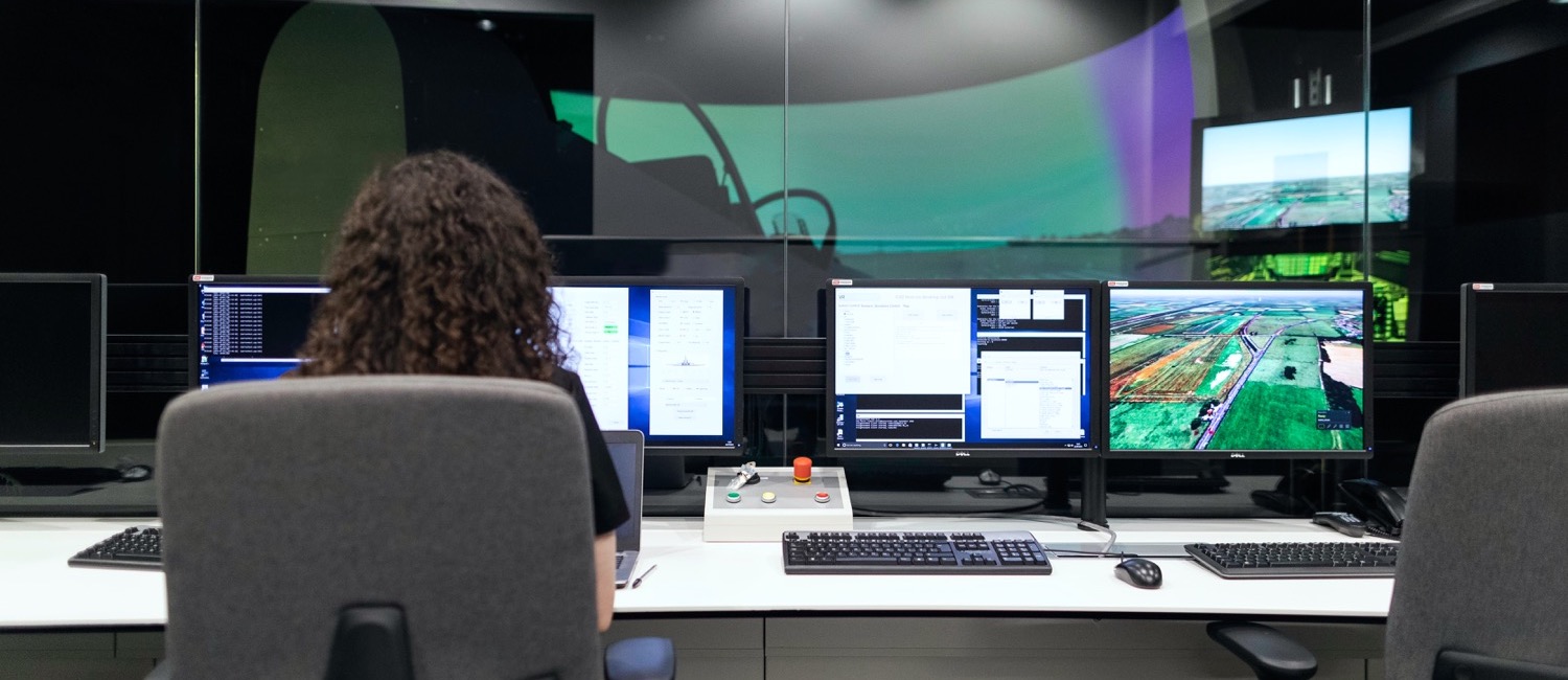 Woman sitting at desk with several computer monitors